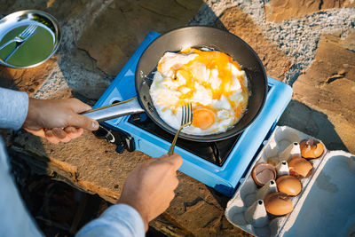 High angle view of man preparing omelet on camping stove