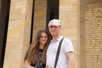 Portrait of smiling couple standing against building