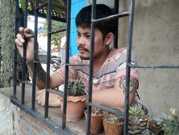 Portrait of young man looking through window