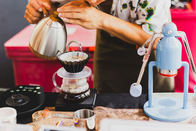 Professional barista preparing coffee using chemex pour over coffee maker and drip kettle.