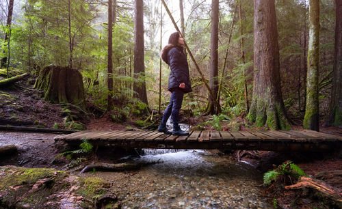 Man standing by trees in forest