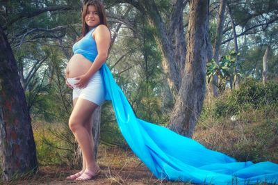 Rear view of young woman standing in forest