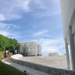 People walking by modern buildings against sky in city