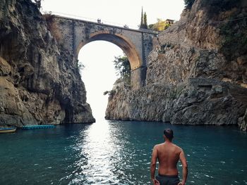 Rear view of shirtless man looking at sea