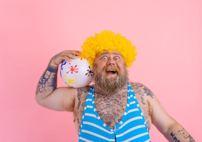 Portrait of man standing against pink background