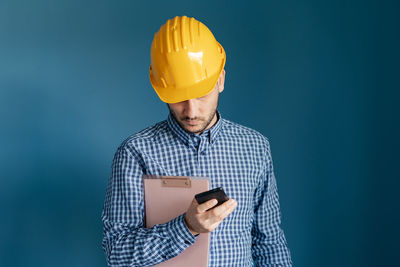 Low angle view of man working against blue sky