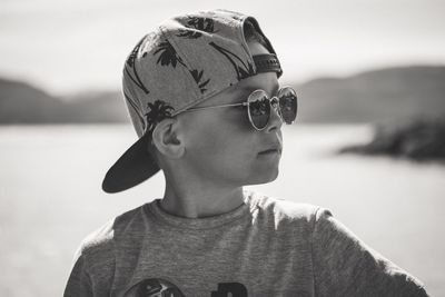 Boy wearing sunglasses and cap against lake