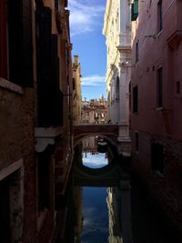 Arch bridge over canal amidst buildings in city