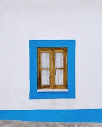 White window on blue wall of building