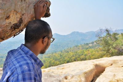 Close-up of man looking at mountains against sky