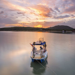 Boat in lake against sky during sunset