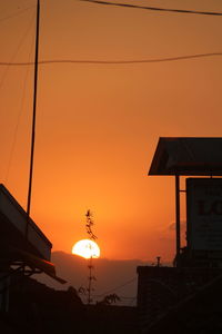 Silhouette buildings against orange sky