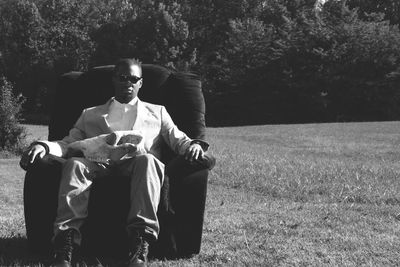 Portrait of man with animal skeleton sitting on armchair at grassy field