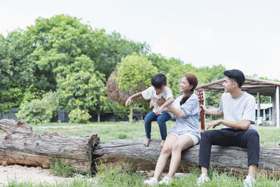 Friends using digital tablet while sitting on field