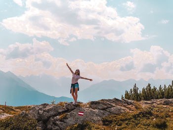 Full length of woman standing on rock against sky