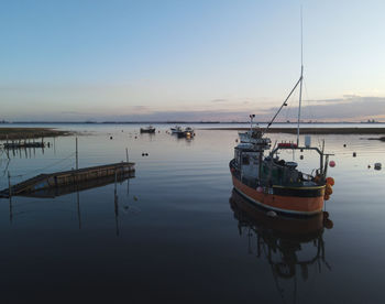 Fishing boats in sea at sunset