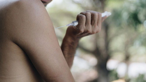 Midsection of man holding syringe