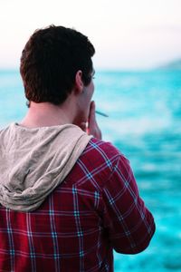 Rear view of man standing by sea against sky