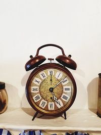 Close-up of clock on table against wall