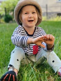 Portrait of cute toddler sitting on grassy field