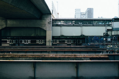 Train on bridge in city against sky