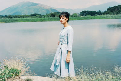 Portrait of young woman standing by lake