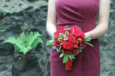 Midsection of woman holding pink flower