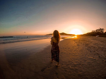 Rear view of woman on beach during sunset