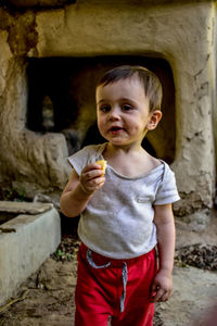 Portrait of boy holding food in abandoned cave