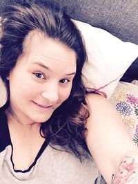 Portrait of woman lying down on bed at home