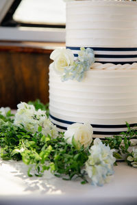 White wedding cake with blue hydrangea and roses decoration, two tiered marine themed desert.