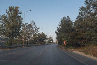 Road amidst trees against clear sky