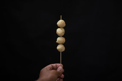 Close-up of hand holding ice cream against black background