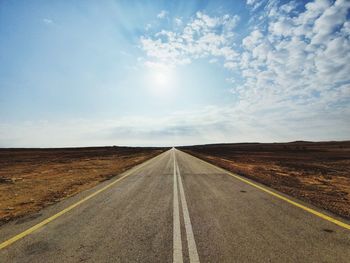 Road passing through land against sky