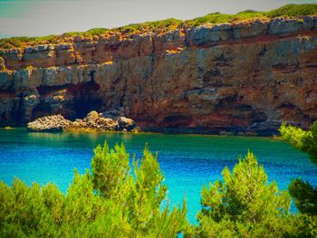 Scenic view of lake by cliff against sky