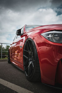 Red modified bmw with black rims from low angle