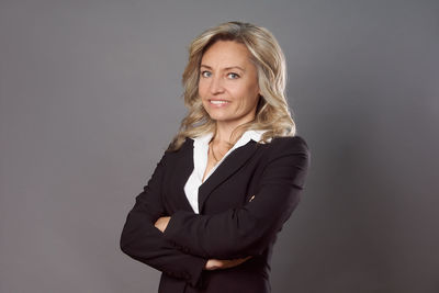 Portrait of young businesswoman standing against gray background