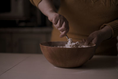 Midsection of woman preparing food in bowl on table