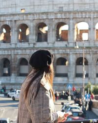 Rear view of woman against coliseum in city