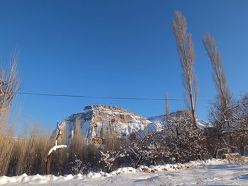 Snow covered land against clear blue sky