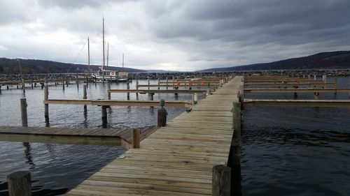 Pier over lake against cloudy sky