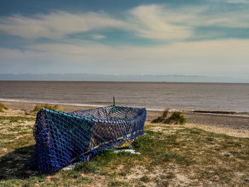 Small fishing boat covered with net on suffolk beach with big sky