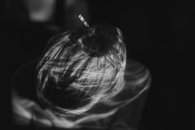 Close-up of woman with apple against black background