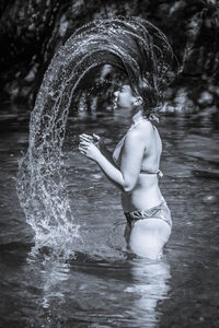 Teenage girl tossing hair while standing in lake