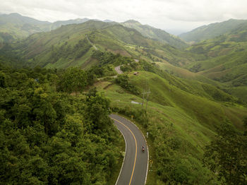 Aerial view of countryside road passing through the lush greenery tropical rain forest mountain