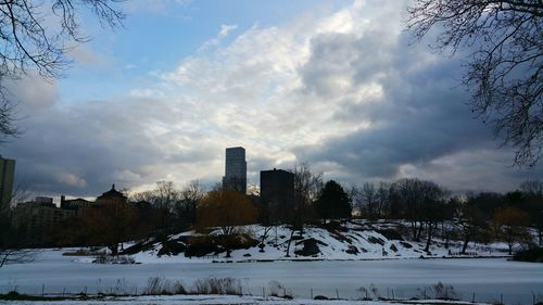 Snow covered field against cloudy sky