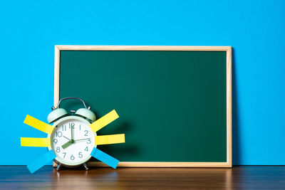Clock on table against blue background