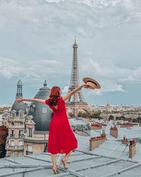 Woman with umbrella against sky in city