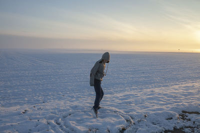 The guy draws a circle with his feet, in the winter in a snowy field