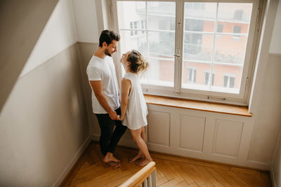 Young couple standing against window